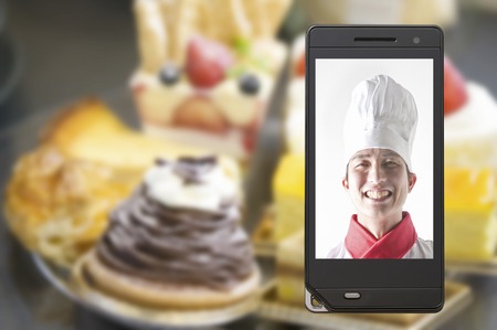 Chef moves to cake and mobile screenの写真素材