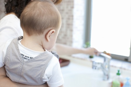 Mother standing in the kitchen and holding a babyの写真素材