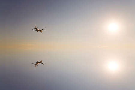 The sun and the airliner reflected on the surface of the waterの写真素材
