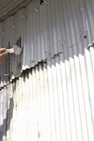 Craftsmen paint the paint on galvanized iron warehouse wallの写真素材