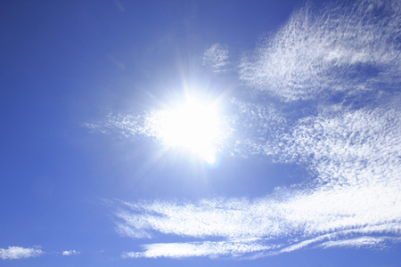 Gaping floating white clouds and sun in the autumn skyの写真素材