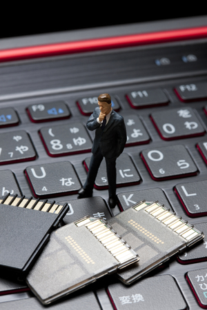 Miniature businessmen to think by looking at the memory cardの写真素材