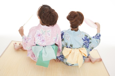sitting in fan to fan  with Rear View of two yukata womanの写真素材