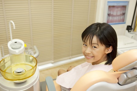 Girl look back to sit in the dentist reclining chairの写真素材