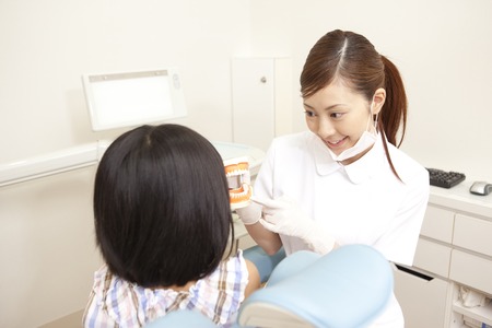 Dental hygienist described in model to girls of patientの写真素材