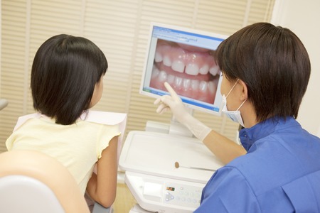Male dentist for the treatment of explanation to girl in the monitorの写真素材