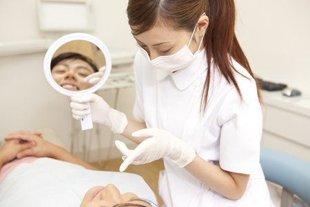 Dental hygienist and male patients to confirm the treatment in hand mirrorの写真素材