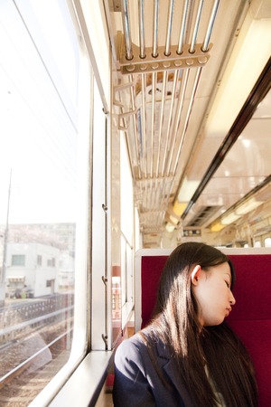 Woman napping in the seat of a trainの写真素材