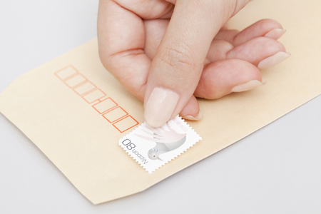 Hand of the woman who put a stamp on the envelopeの写真素材