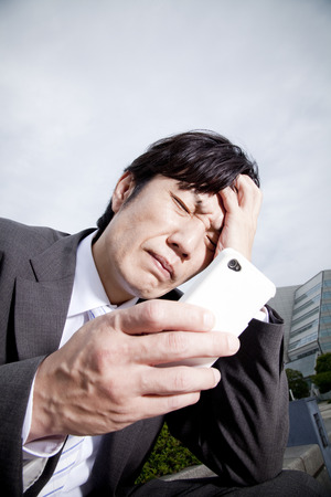 Businessman facing his head to look at the smartphoneの写真素材
