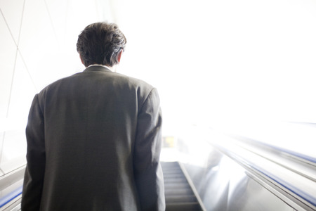 From behind businessman climb the escalatorの写真素材