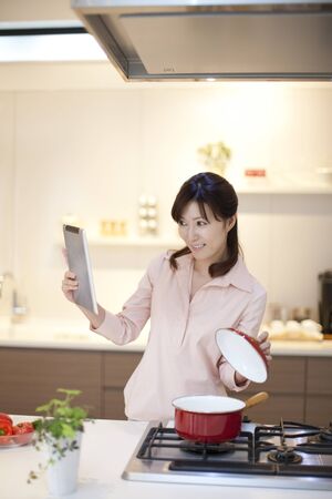 Women cooking while watching a Tablet-type computerの写真素材