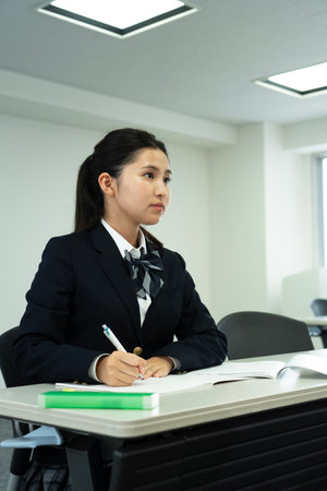 Asian teenage girl in high school uniform studying in class