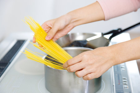 Woman cooking spaghetti in the kitchenの写真素材