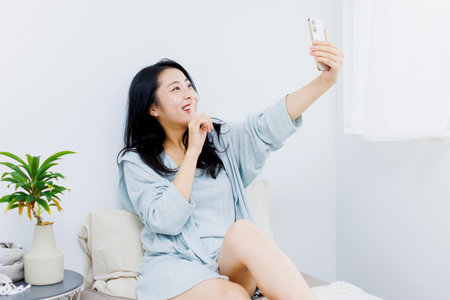 Asian woman taking self photograph with mobile phoneの写真素材