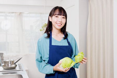 Asian woman with lettuce in the kitchenの写真素材