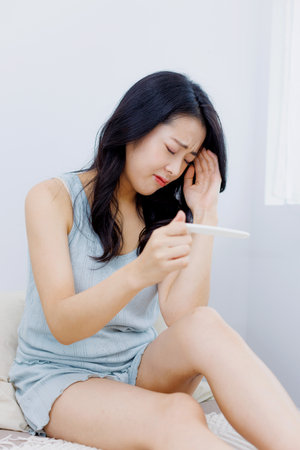 Asian woman disappointed with the result on pregnancy test kitの写真素材