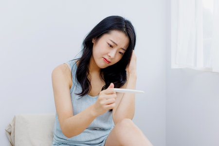 Asian woman disappointed with the result on pregnancy test kitの写真素材