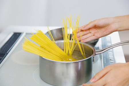 Woman cooking spaghetti in the kitchenの写真素材