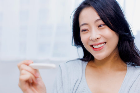 Asian woman happy with the result on pregnancy test kitの写真素材