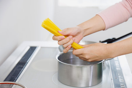 Woman cooking spaghetti in the kitchenの写真素材