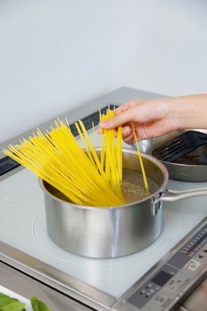 Woman cooking spaghetti in the kitchenの写真素材