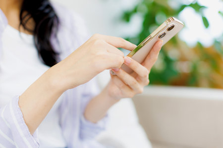 Asian woman using her mobile phone in the living roomの写真素材