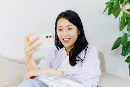 Asian woman watching video on her mobile phoneの写真素材