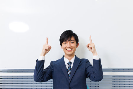 Young Japanese man in office attire pointing upwardの写真素材