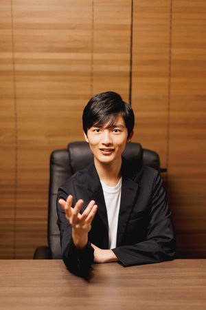 Young Japanese man smiling and gesturing at the camera