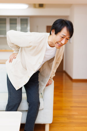 Mature Japanese man suffering from back pain at homeの写真素材