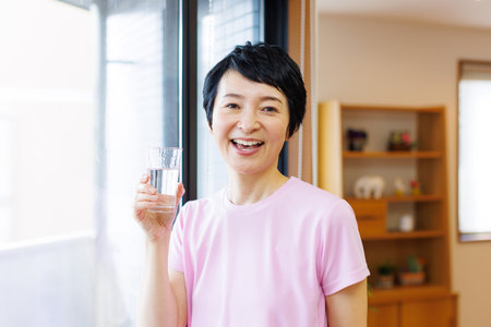 Mature Japanese woman with a glass of waterの写真素材