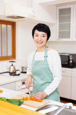 Mature Japanese woman doing food preparation at kitchenの写真素材