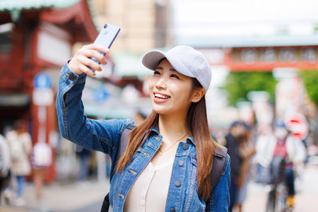 Asian woman taking photograph with mobile phoneの写真素材