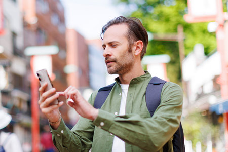 Caucasian man walking in street with mobile phoneの写真素材