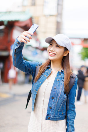 Asian woman taking photograph with mobile phoneの写真素材