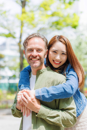 Asian woman giving Caucasian man a back hugの写真素材