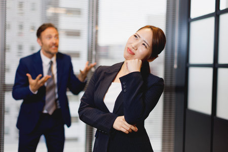 Businesswoman contemplating while frustrated colleague is looking at herの写真素材