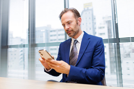 Caucasian man using his phone at workの写真素材
