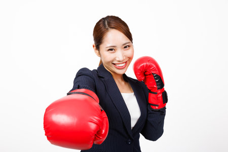 Asian businesswoman posing with fighting glovesの写真素材