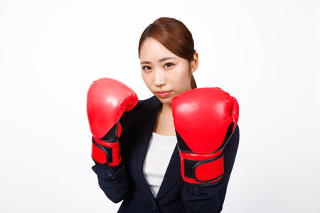 Asian businesswoman posing with fighting glovesの写真素材