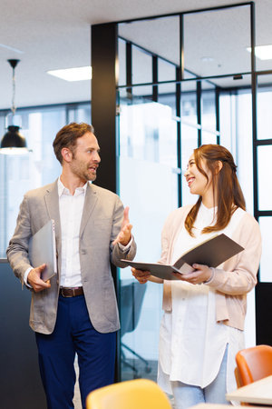 Caucasian businessman and Asian businesswoman in smart casual attire having a discussionの写真素材