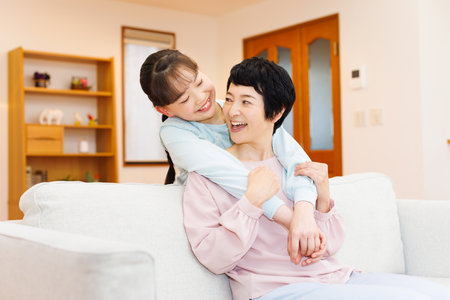 Happy Japanese girl with her grandmother at homeの写真素材