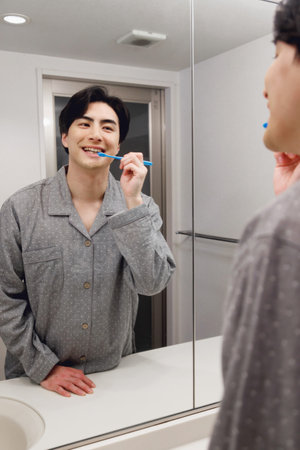 Japanese man in pajamas brushing his teethの写真素材