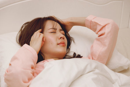 Japanese woman feeling sick in her bedの写真素材