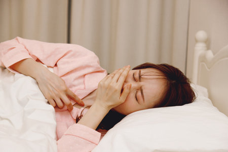 Japanese woman feeling sick in her bedの写真素材