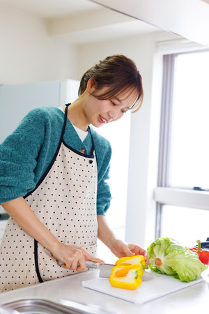 Japanese woman cutting ingredients for cookingの写真素材
