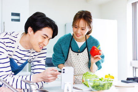 Japanese couple preparing to cook in kitchenの写真素材
