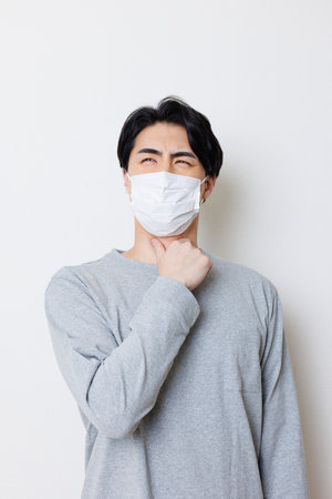 Japanese man with face mask feeling sickの写真素材