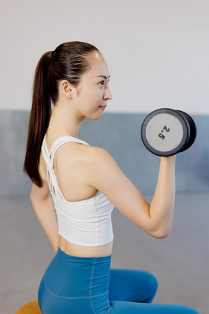 Young Asian woman training with a dumbbell